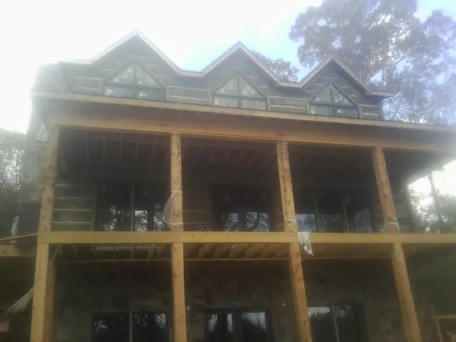 Dormers and porch framing on a large log home under construction — Roof Coating work by our crew in Moss Point