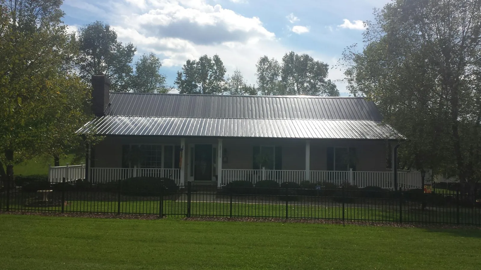 Gray metal roof on a brick ranch with a full width front porch — Gutter Guard Installation work by our crew in Moss Point