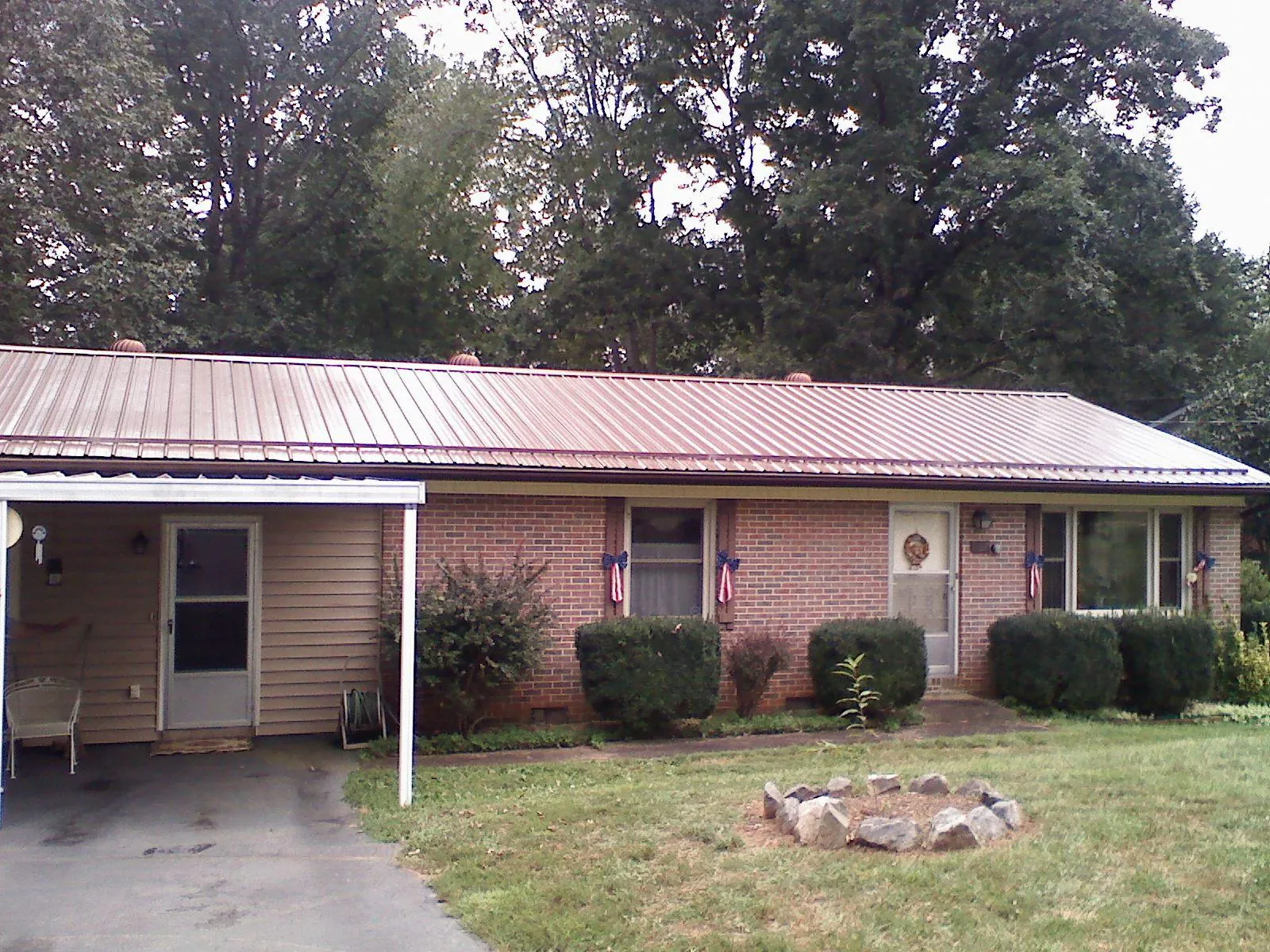 Bronze metal roof and carport on a brick ranch home — Roof Repair work by our crew in Moss Point
