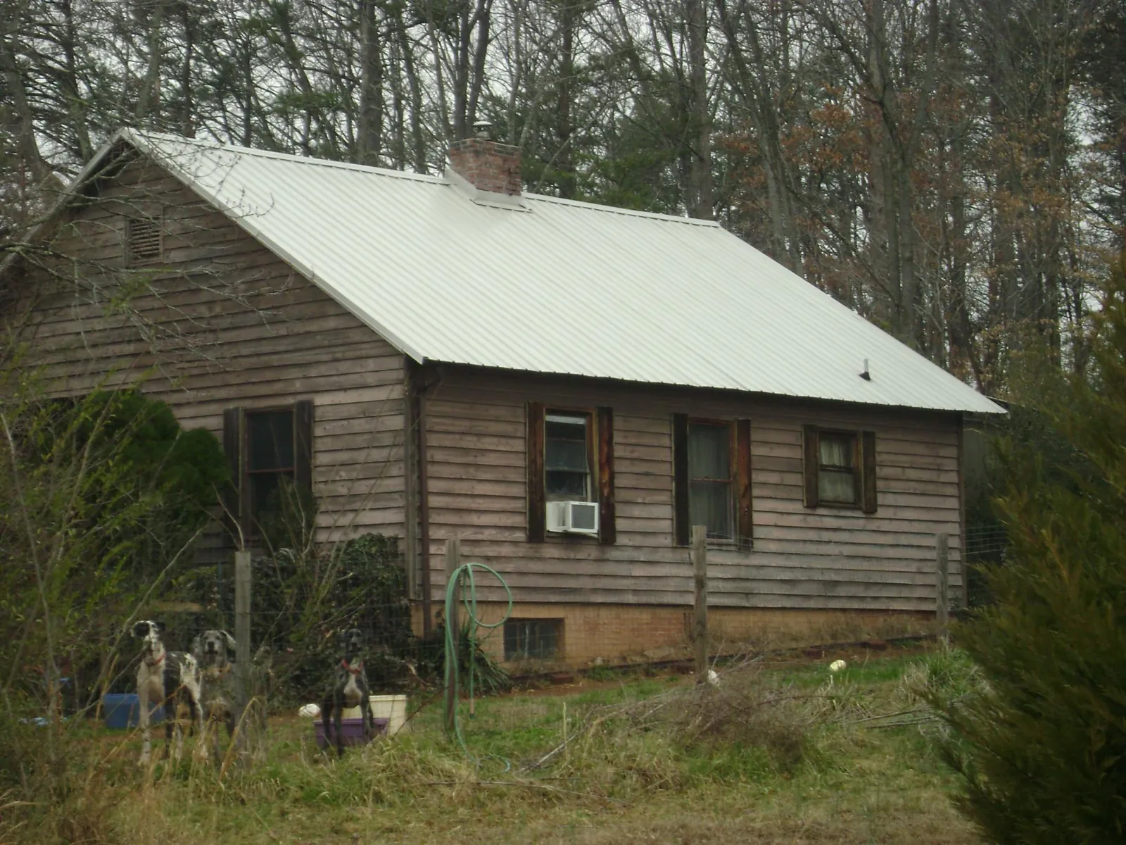 White metal roof on an old wood sided farmhouse, from a Metal Roof Installation job in Moss Point